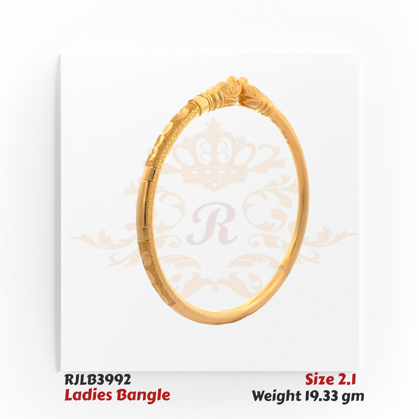 Angled view of a gold ladies bangle featuring an ornate central motif with layered scrollwork, subtle floral engravings, and fine detailing along the band for an elegant traditional touch. Model RJLB3992.