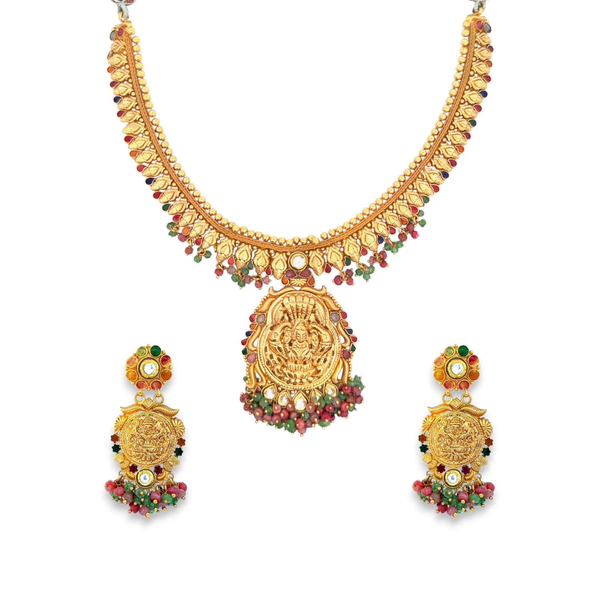 Traditional 22kt gold temple necklace set featuring a detailed Lakshmi motif pendant, red and green gemstone accents, and intricate gold bead patterns. Paired with matching earrings, ideal for bridal and festive wear from Regal Jewels Chicago.