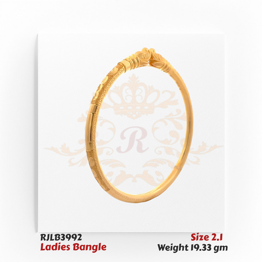 Angled view of a gold ladies bangle featuring an ornate central motif with layered scrollwork, subtle floral engravings, and fine detailing along the band for an elegant traditional touch. Model RJLB3992.