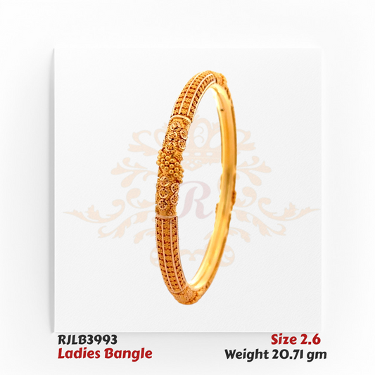 Angled view of a gold ladies bangle featuring intricate floral and swirl engravings, with a raised dome cluster centerpiece and textured detailing for a rich traditional appeal. Model RJLB3993.