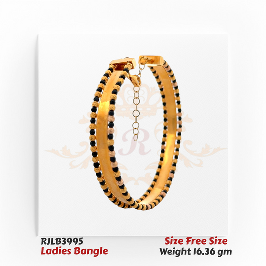 Angled view of a polished gold ladies bangle embellished with alternating black and gold bead accents along the edges, secured with a clasp and safety chain for a classic yet striking look. Model RJLB3995.