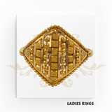 This is an image of a gold ladies ring with a detailed square design featuring various raised geometric patterns and embellishments. The label "LADIES RINGS" is present at the bottom of the image.